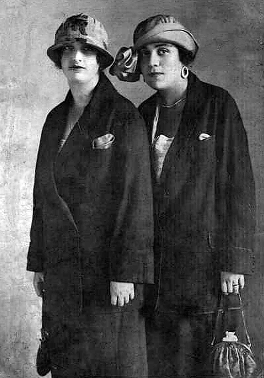 Dua perempuan berpose dengan memakai topi.