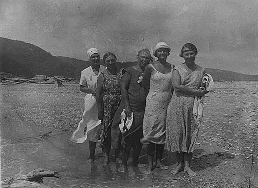 Lima perempuan berpose di tepi pantai.
