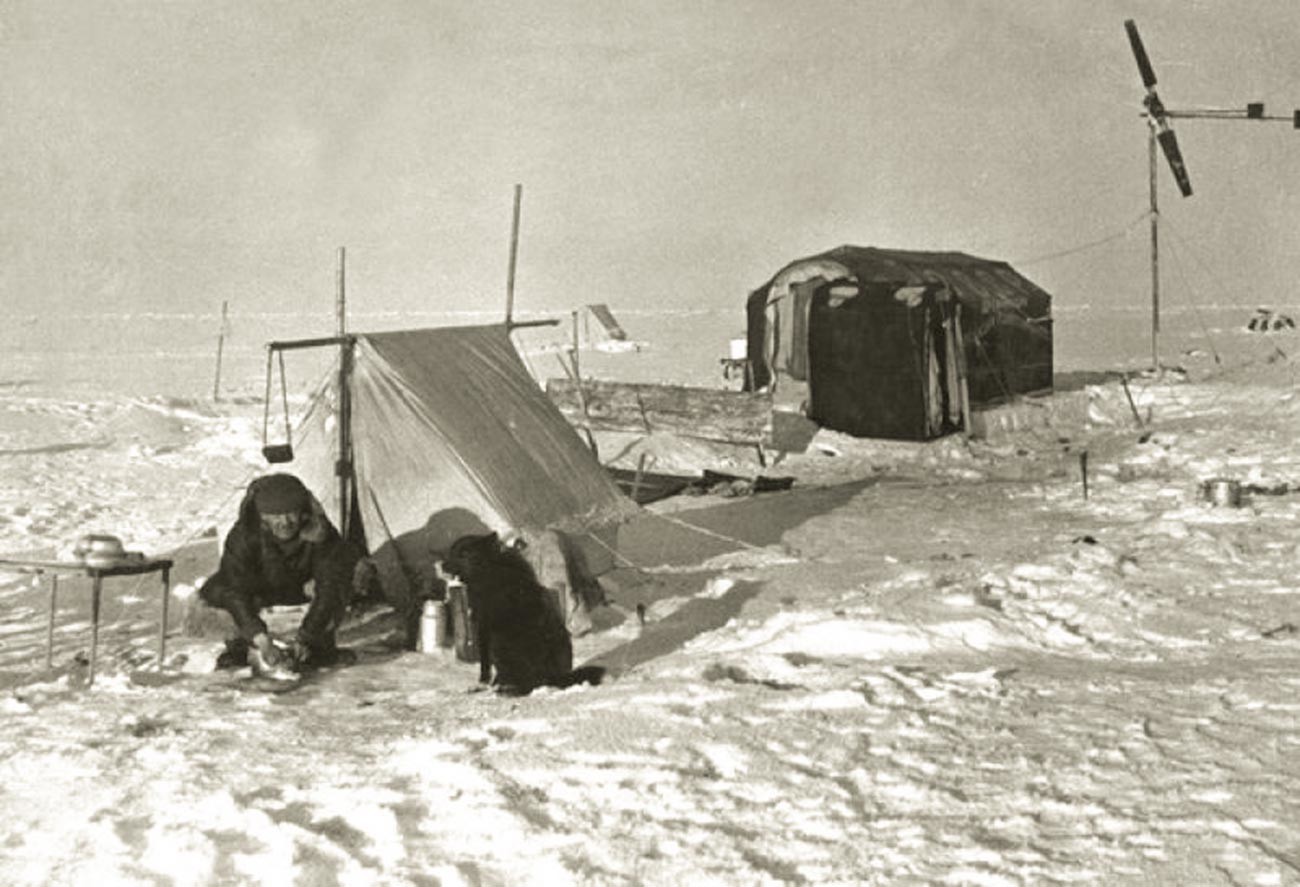 Ернст Кренкељ, дежурен во кујната на станицата „Северен пол“. Покрај него е кучето Весели.

