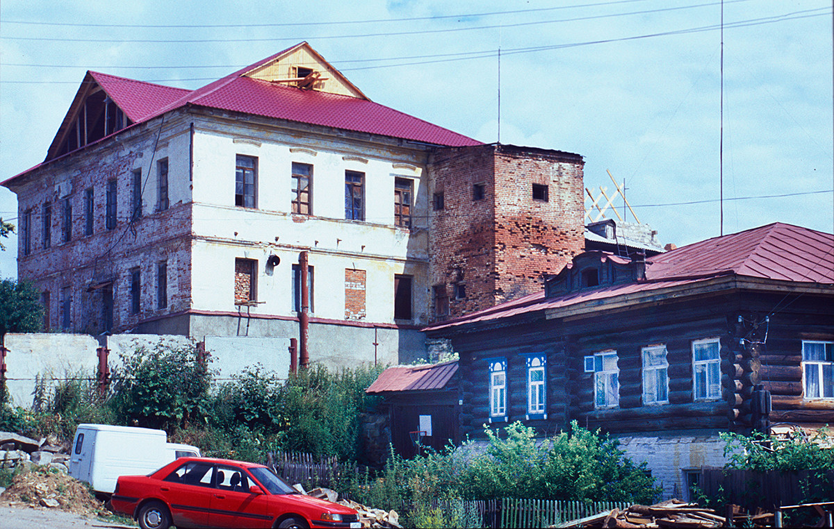 Local Administration (zemskaya uprava) building (19th-century). Right: late 19th-century log house with iron roof (example of workers' housing). July 14, 2003.