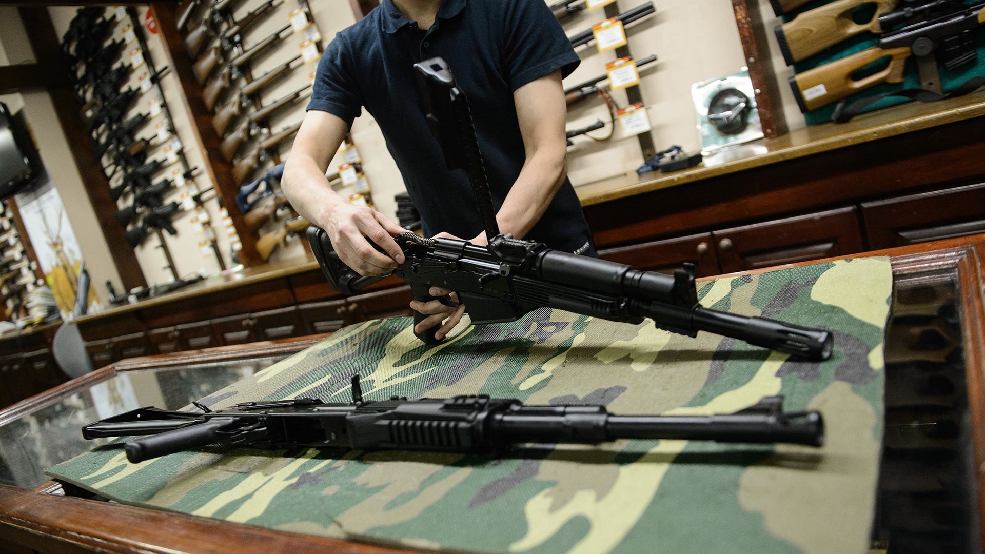 An assistant in a weapon store in Chelyabinsk dissembles a rifle 