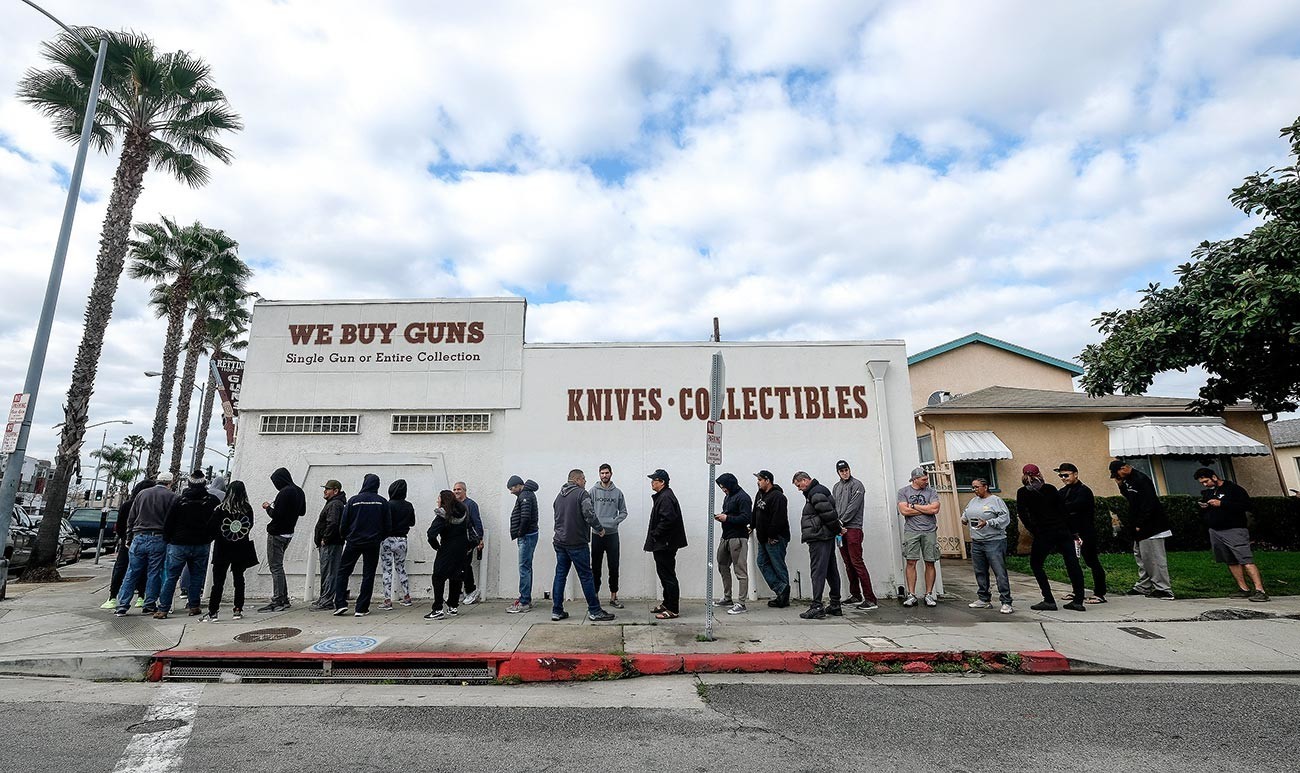 Ljudje stojijo v vrsti pred prodajalno z orožjem v Culver Cityju v Kaliforniji. Skrbi okoli koronavirusa so privedle do nakupovalne mrzlice tako v trgovinah z živili kot z orožjem. 15. marca, 2020. 