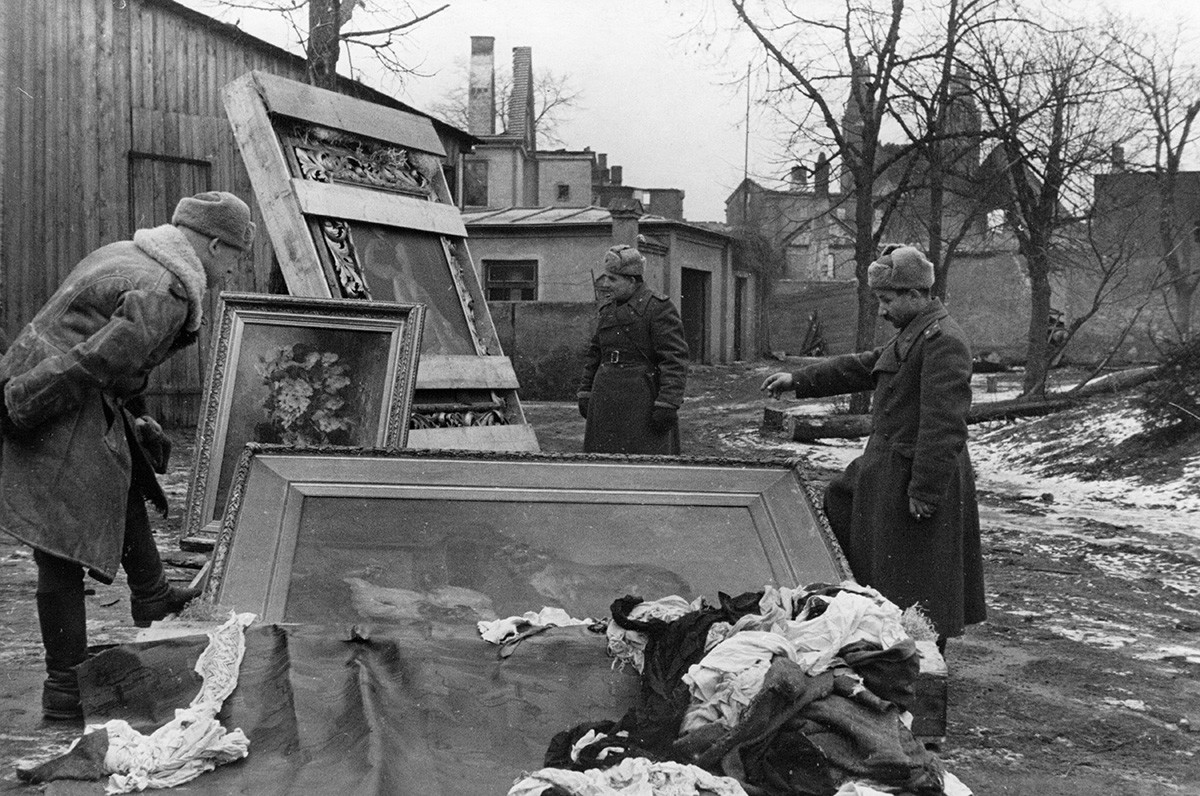 Soldaten der Roten Armee mit Gemälden, die 1945 von den Deutschen aus dem Palast Peterhof gestohlen wurden.

