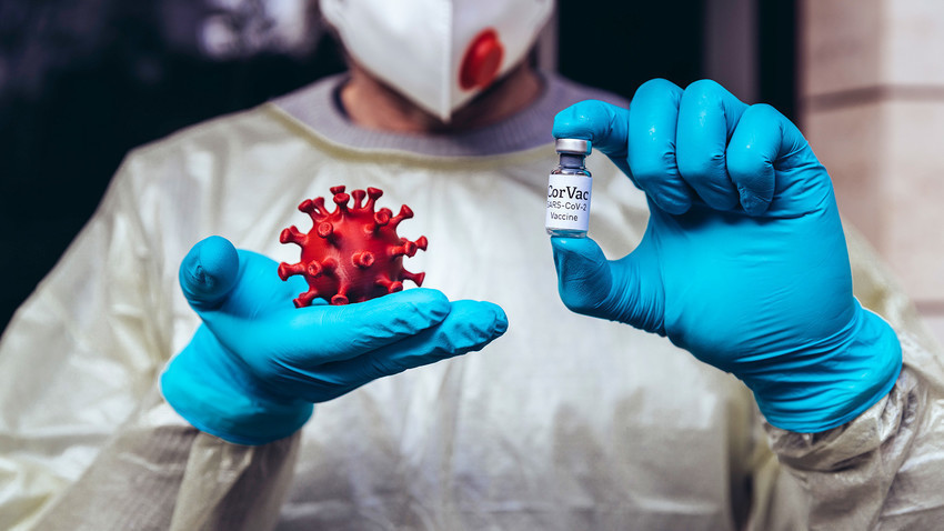 Медицински работник држи модел на вирусот Корона и вакцина.