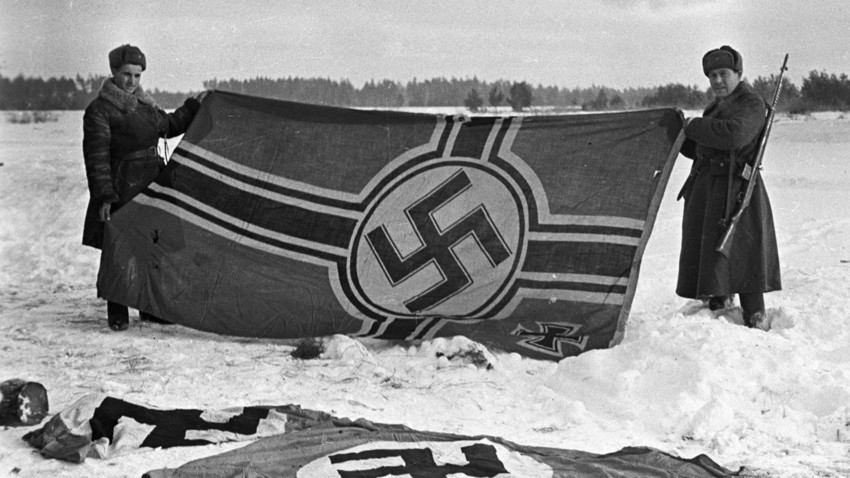 Dois soldados soviéticos mostrando primeira bandeira nazista capturada em batalhas perto de Kalinin, 1941