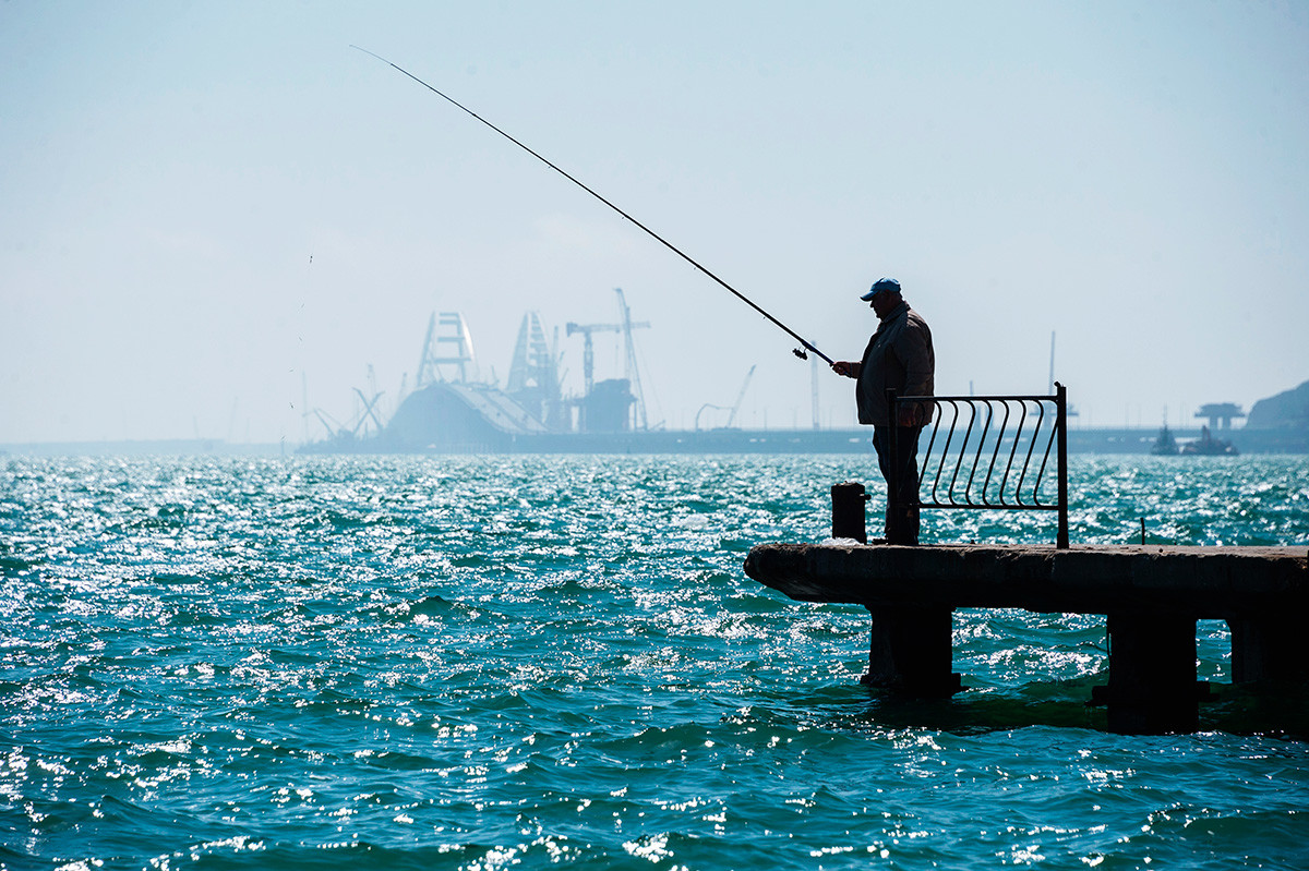 Moški lovi ribe na mestnem nabrežju v Kerču. 