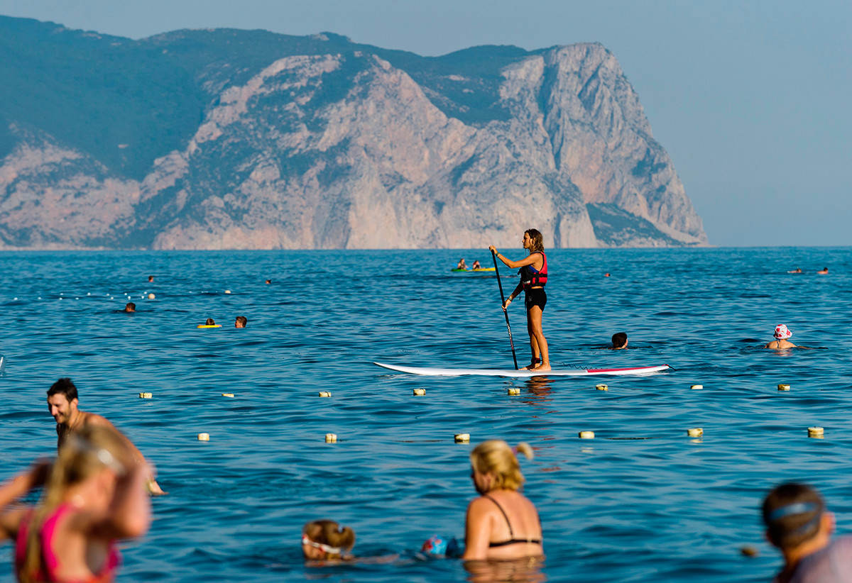 The girl is engaged in SUP surfing in the waters of the Jasper beach at Cape Fiolent in Sevastopol