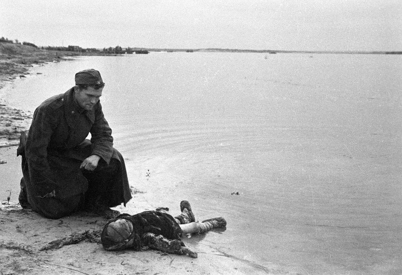 Съветски войник на брега на Днепър скърби за убито дете.