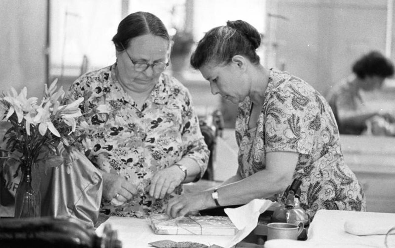 Women packing a present in the paper.