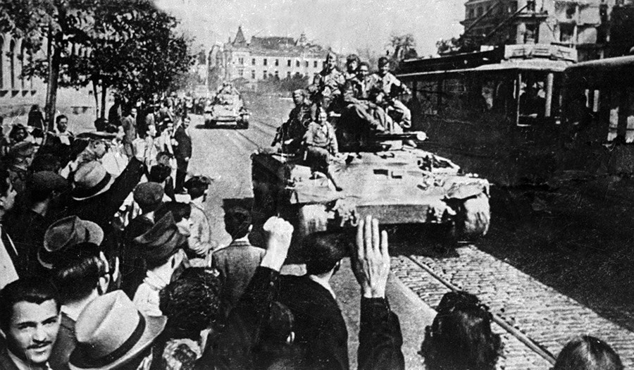 Soldados soviéticos son recibidos por los residentes de Bucarest (Rumania) cuando entran en la ciudad en estos vehículos blindados