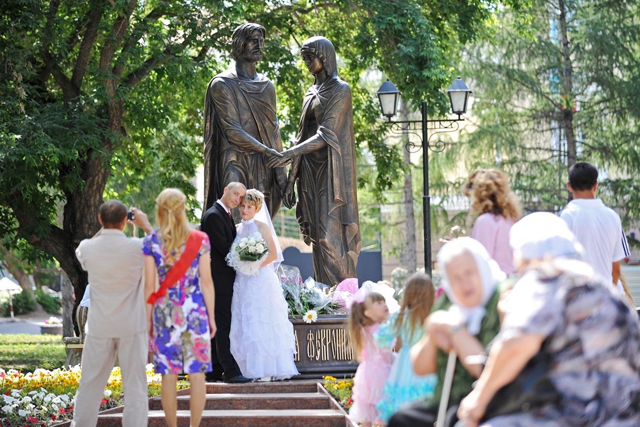 Mladoporočenca se fotografirata pri spomeniku Petra in Fevronije v Omsku.
