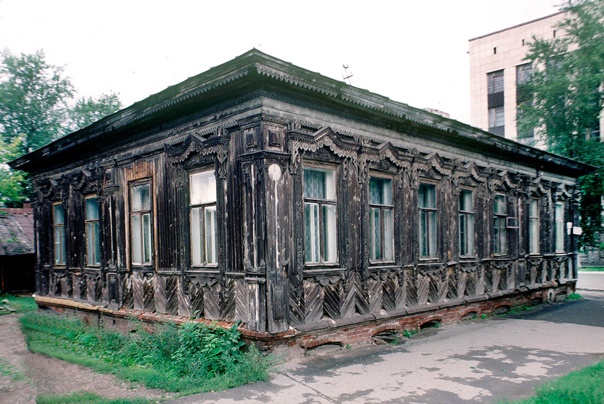 Maison en bois du XIXe siècle, rue Monasteri N°26. Structure en rondins avec revêtement en planches. Le repavage fréquent de la rue obscurcit le niveau du sous-sol en brique