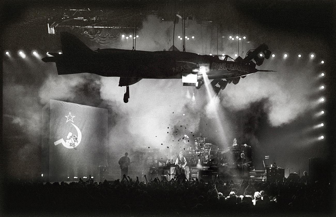 Пол Маккартни свири Back In the USSR по време на Световното турне. Над сцената е окачен самолет. От ляво надясно: Роби Макинтош, Пол Уикенс, Пол Маккартни, Крис Уитън, Линда Маккартни и Хамиш Стюарт. Ротердам, Холандия, 11 ноември 1989 г.