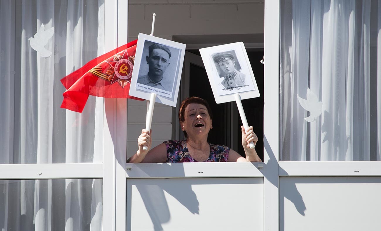 Una cittadina di Tyumen con il ritratto dei veterani della Grande guerra patriottica canta una canzone della guerra insieme ai partecipanti della manifestazione “La parata a casa”
