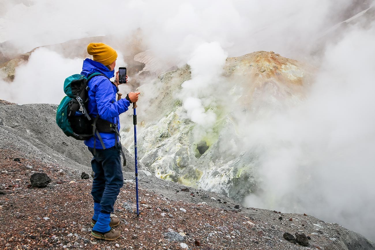 Turist na polju fumarol v kraterju vulkana Mutnovski.
