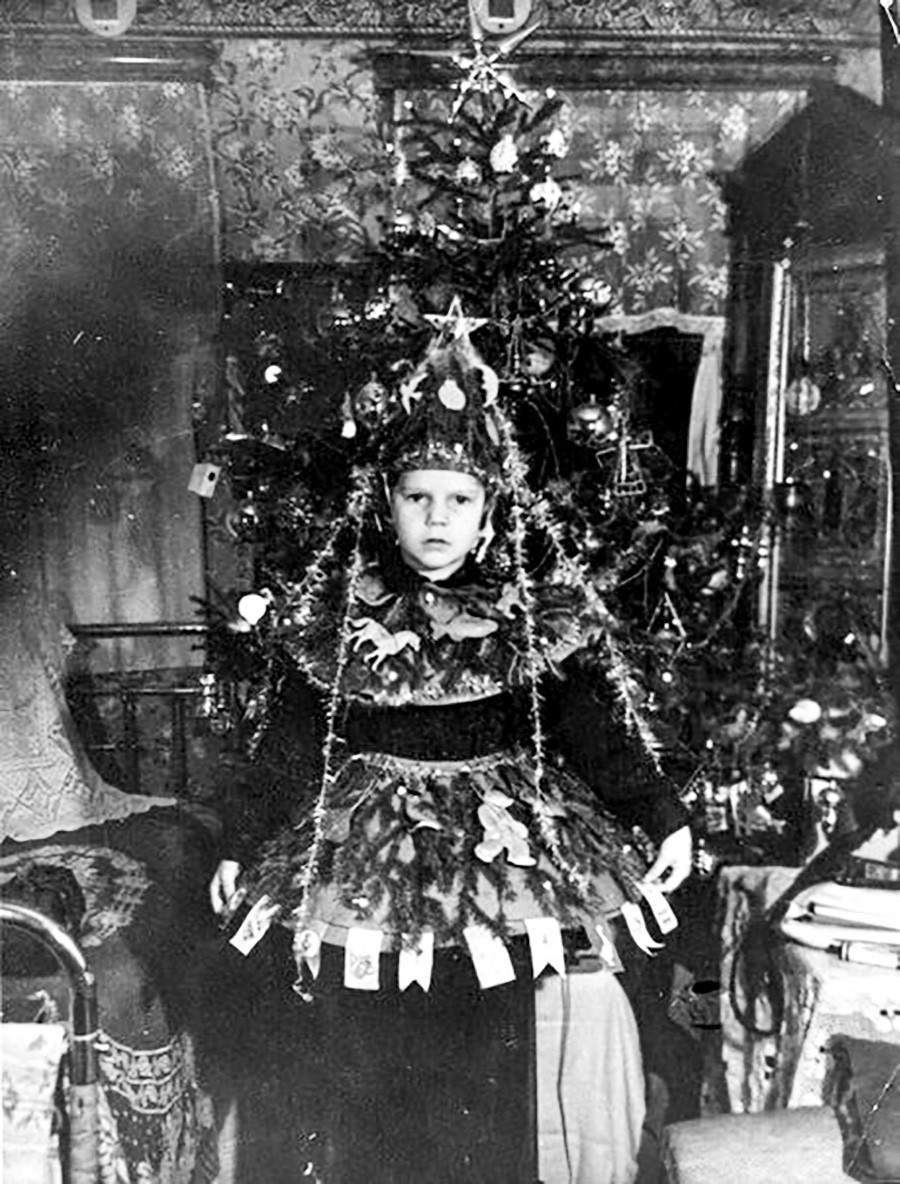 Enfant en costume de sapin, placé devant un sapin...