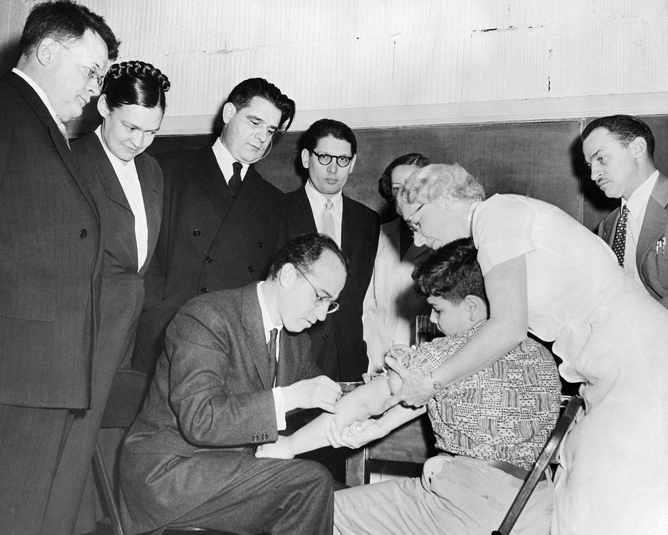 Cientistas russos em visita aos Estados Unidos observam Dr. Jonas Salk administrar injeção de sua vacina antipólio em Paul Anolik, de 9 anos
