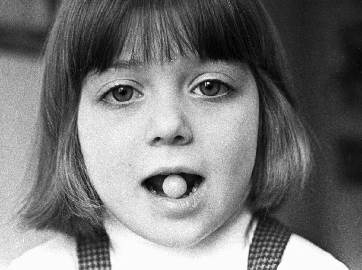 Une fille tient une capsule avec un vaccin entre ses dents à l'Institut des infections de la poliomyélite et de l'encéphalite