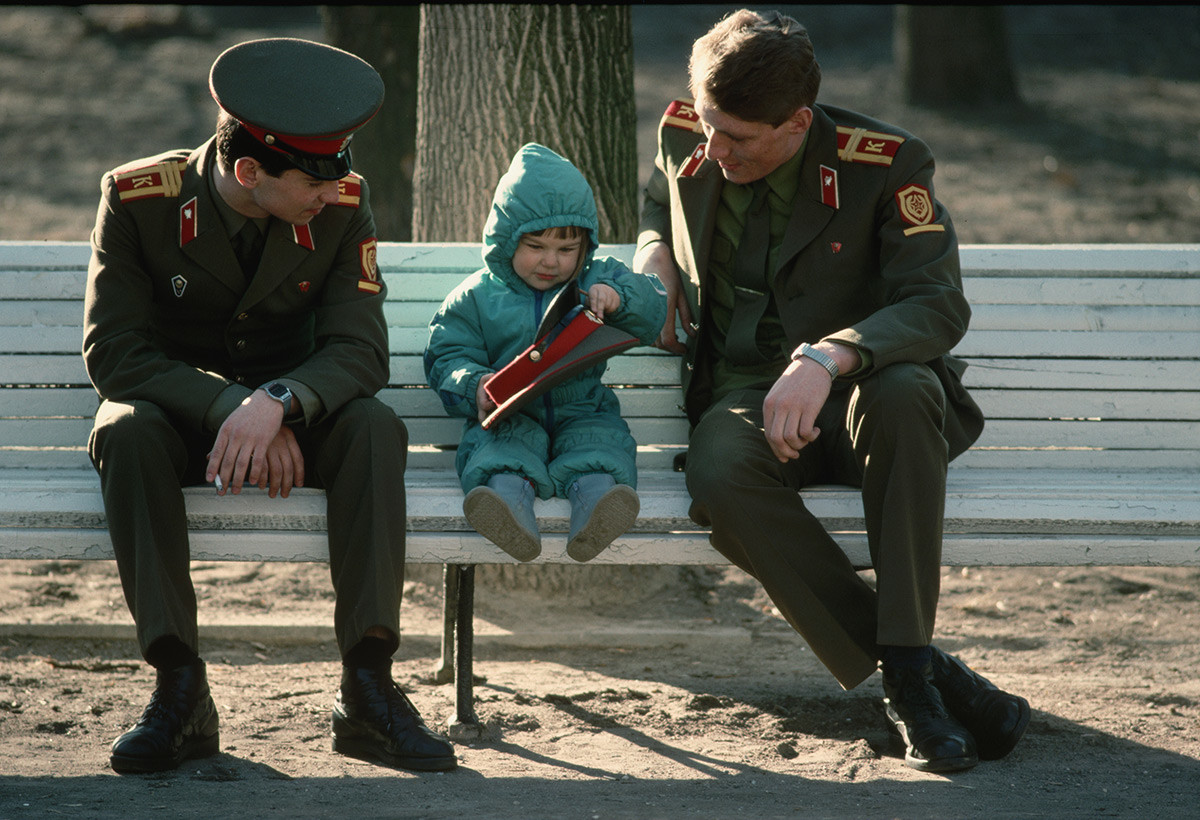 子どもとともに公園のベンチに座る兵士たち