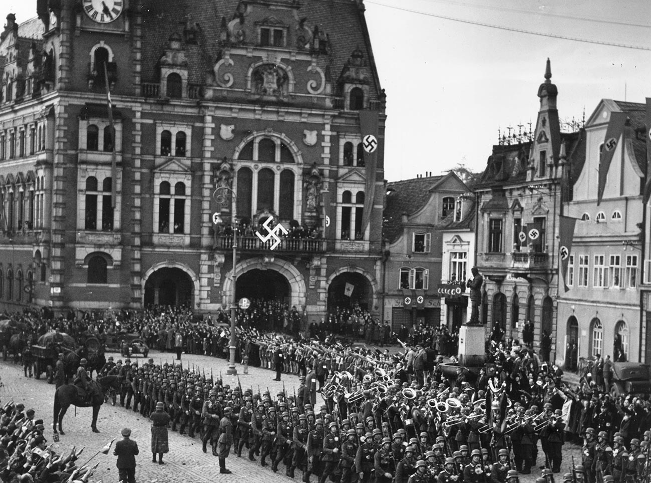 Les troupes de l'armée allemande défilent en territoire tchécoslovaque sur la place de la ville de Rumburk, qui a été décorée de bannières à croix gammée.