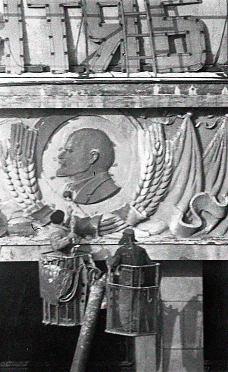 Zwei Arbeiter reinigen das Lenin-Porträt in einem Kolchos.