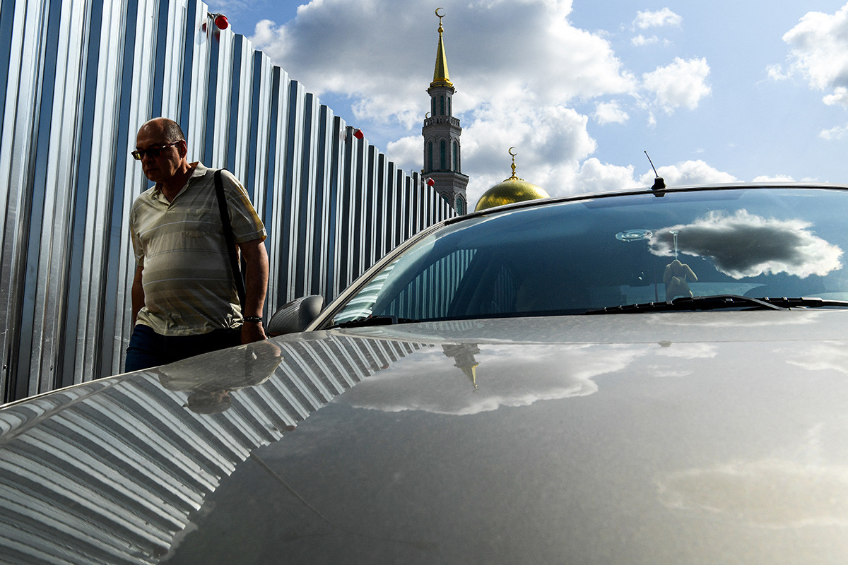 Пролазник у шетњи дуж металне ограде којом је ограђен грађевински простор у близини Саборне џамије. Москва, 7. август 2019.