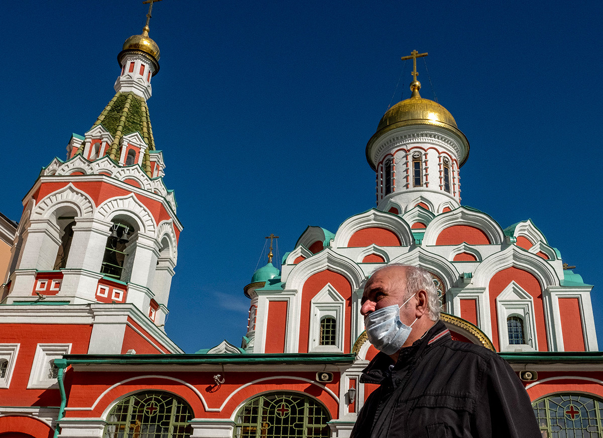 A man wearing a face mask to protect against the coronavirus disease walks past a Russian Orthodox cathedral on Red Square in central Moscow on October 2, 2020