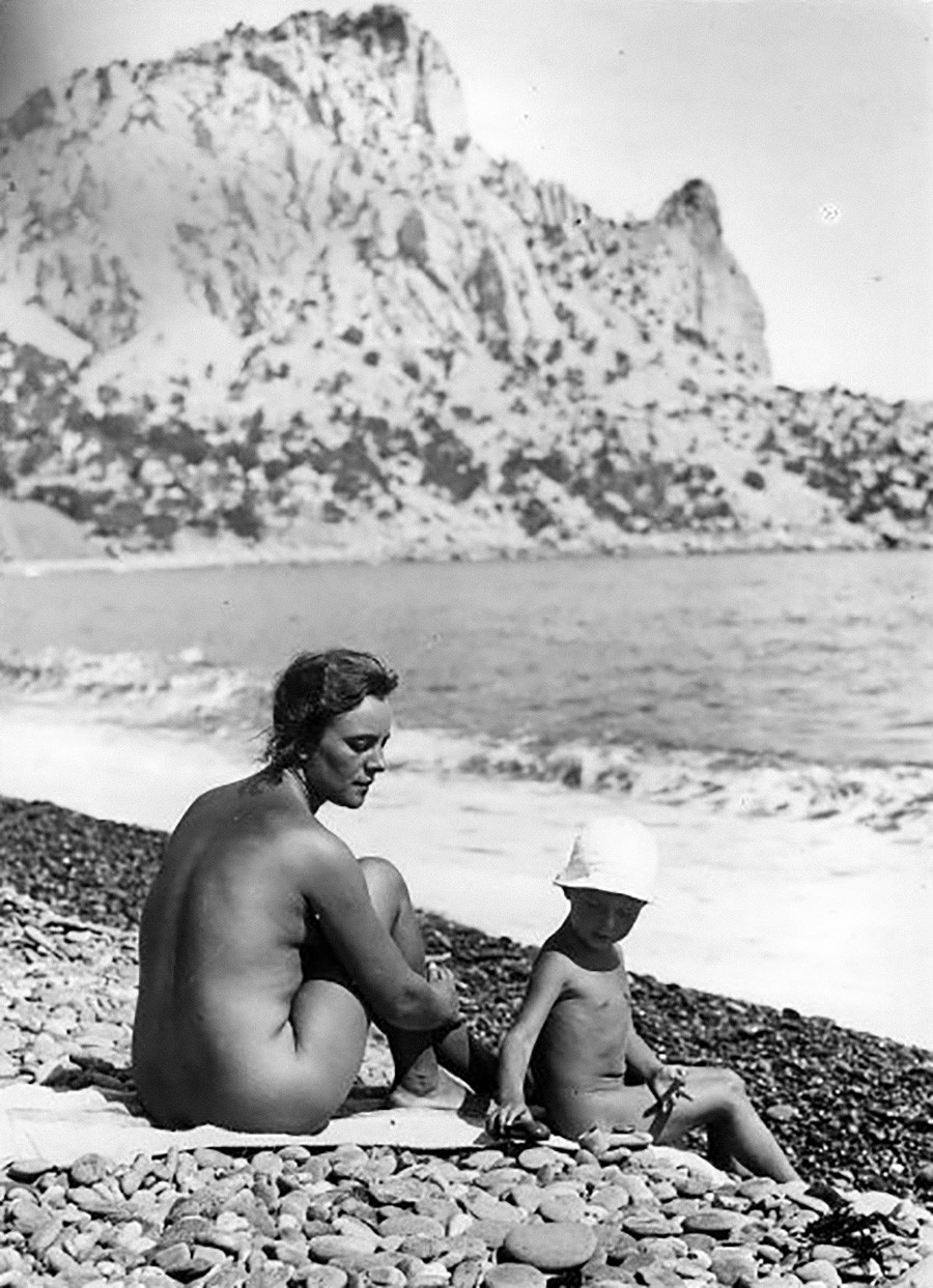 Eine Frau und ihr Kind sonnen sich an einem Strand auf der Krim, 1925.