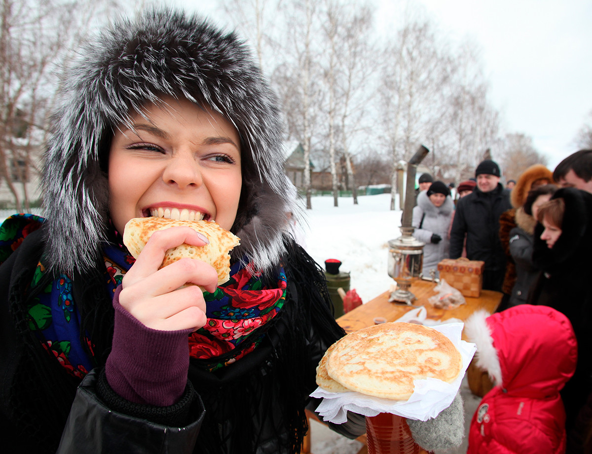 リャザンにて、マースレニツァ（バター祭り）でブリヌィ（パンケーキ）を楽しむ若い女性