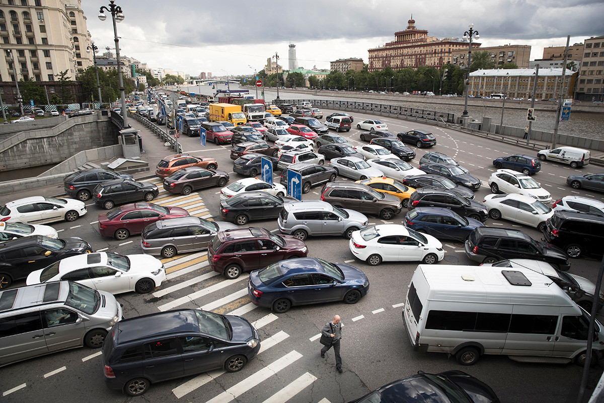 A man crosses a street during a traffic jam on the embankment of the Moskva River in downtown Moscow