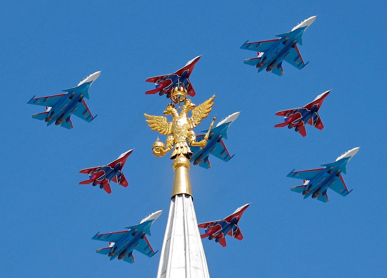 Jet tempur MiG-29 regu aerobatik Strizhi dan jet tempur Su-30 regu aerobatik Russkiye Vityazi terbang dalam formasi selama parade Hari Kemenangan di Moskow.