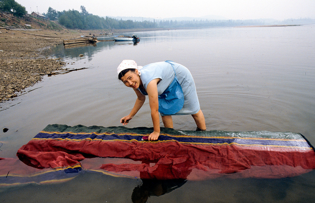 Жительница во время стирки ковровой дорожки на реке Бирюса, Красноярский край.