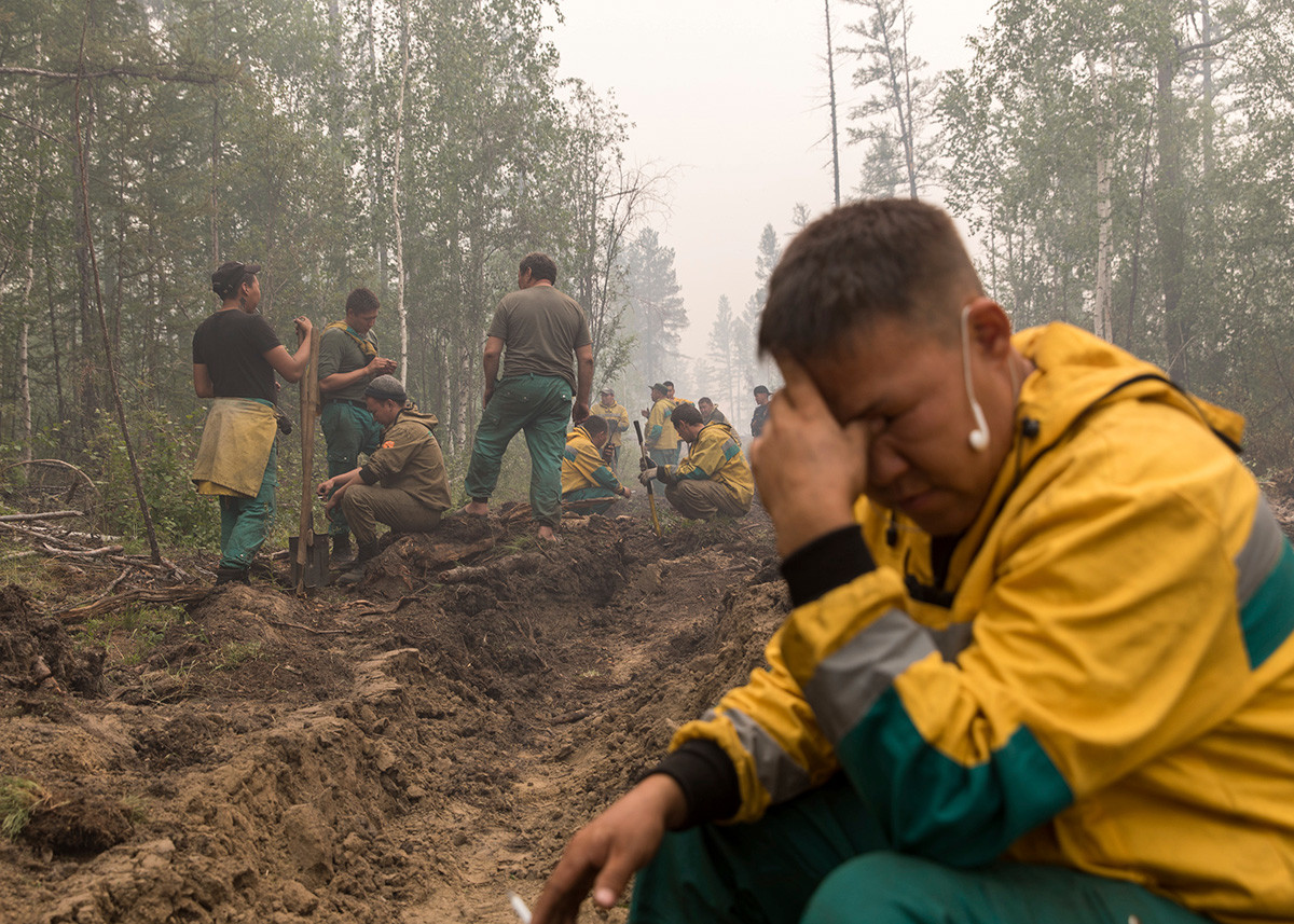 Employés du service iakoute de gestion forestière creusant une tranchée pour contrer l'avancée du feu, à proximité du village de Magaras