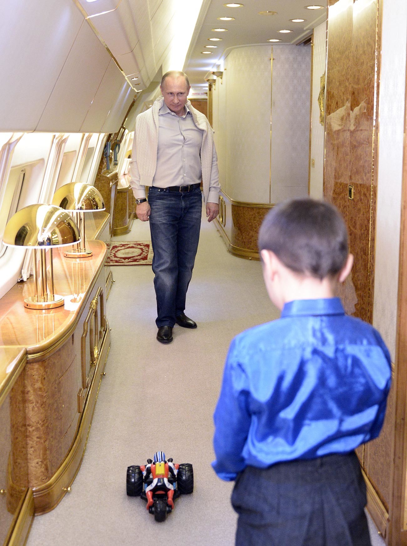 Президент России Владимир Путин и сын младшего сержанта Баира Банзаракцаева, погибшего при ликвидации последствий наводнения на Дальнем Востоке, Галсан играют на борту президентского самолета. 31 декабря 2013. 