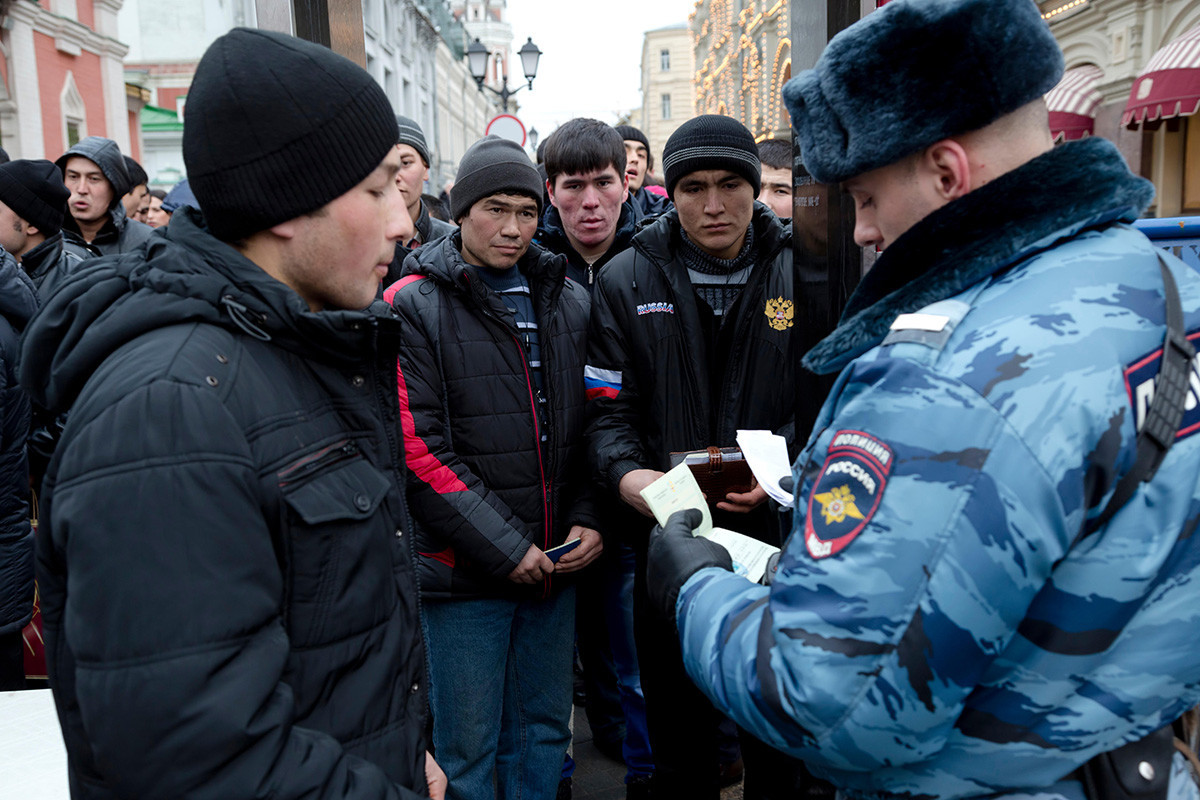 Policial verifica documentos de trabalhadores migrantes da Ásia Central na entrada da Praça Vermelha em Moscou