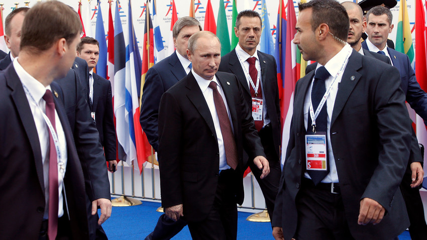 Vladimir Putin is surrounded by bodyguards as he leaves the Europe-Asia summit (ASEM) in Milan on October 17, 2014. 
