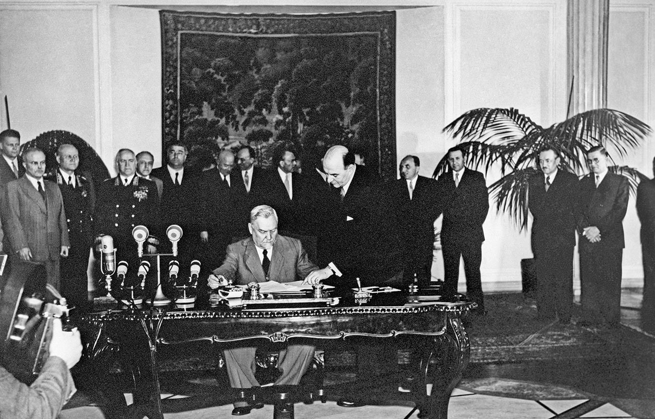 Председателят на Министерския съвет на СССР Николай Александрович Булганин (в центъра) в присъствието на членове на съветската делегация и делегации на други държави подписва Договора за приятелство, сътрудничество и взаимопомощ