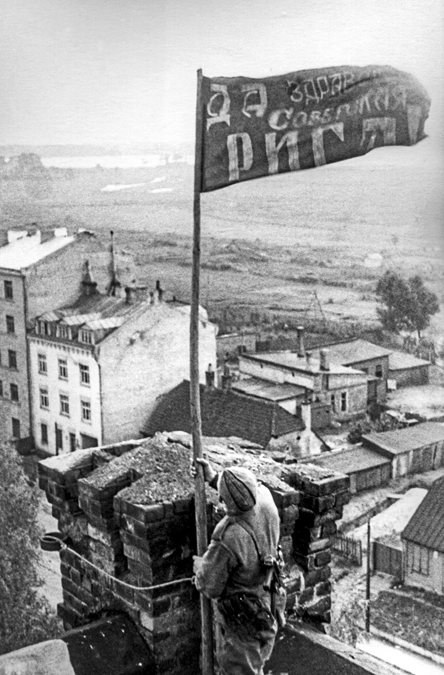 Riga. Lettische SSR. UdSSR. Ein Soldat hisst das Rote Banner über der Stadt, nachdem sie im Zweiten Weltkrieg von den Nazi-Invasoren befreit wurde.
