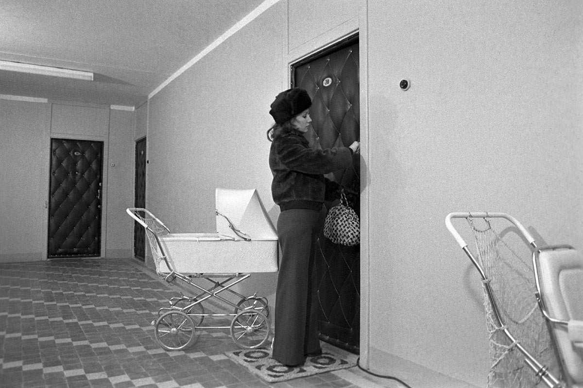 A woman opening a door covered in fabrikoid (dermatin), cheap artificial leather.