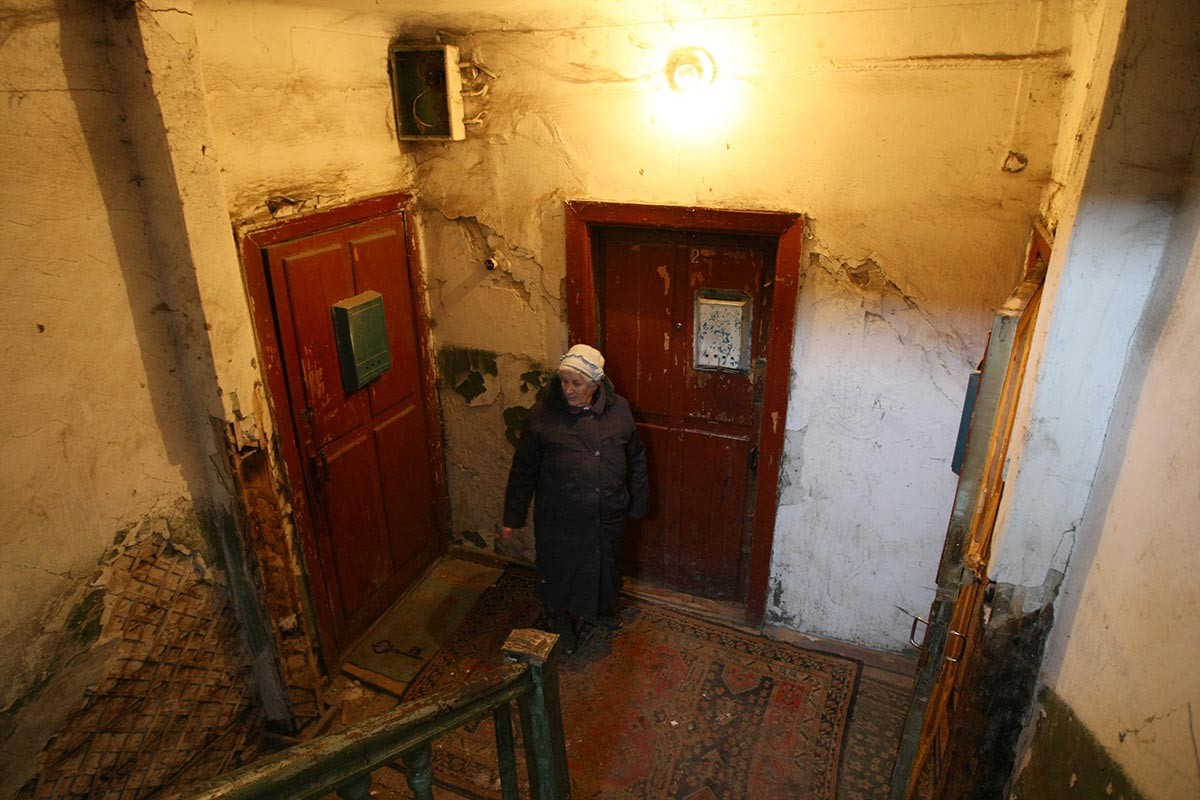 A woman standing in the staircase of her apartment house in Novosibirsk, Russia. Notice the old wooden doors.
