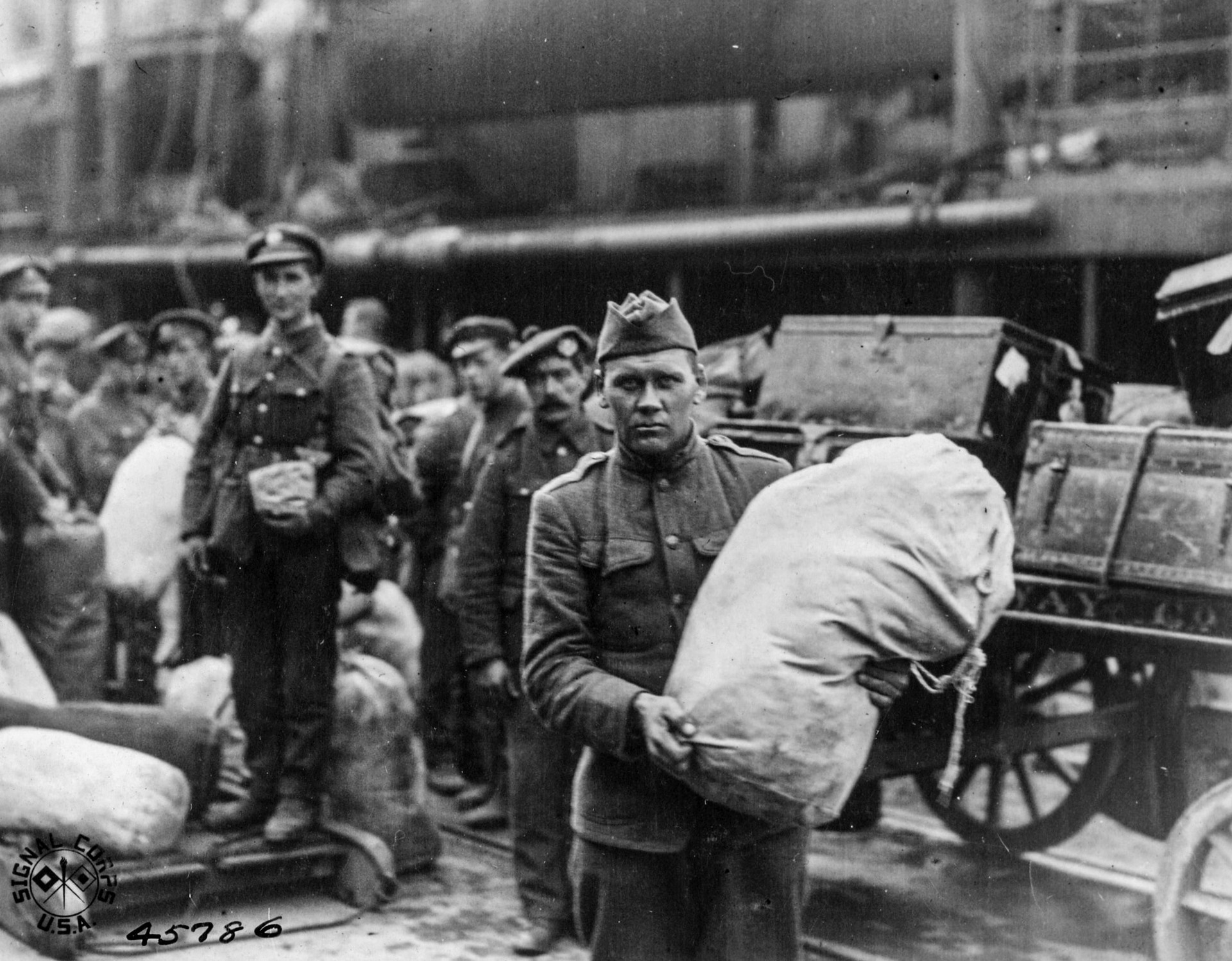 Soldado norte-americano faz  pausa para tirar fotografia enquanto carrega suprimentos em navio com destino à Rússia em 1918.