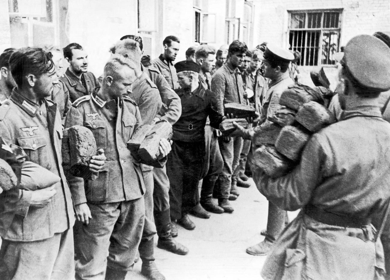 German prisoners of war captured by Russian forces are fed bread by the Russian soldiers during the Second World War. 9th August 1941.