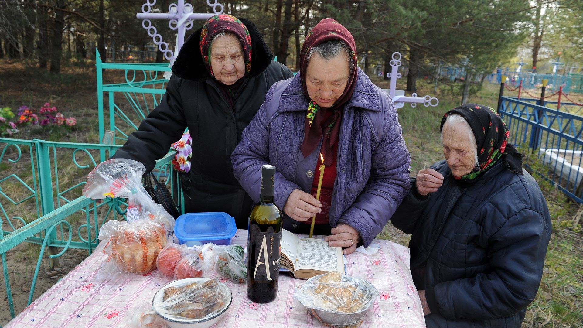 Old women commemorate their departed friend at her gravesite.