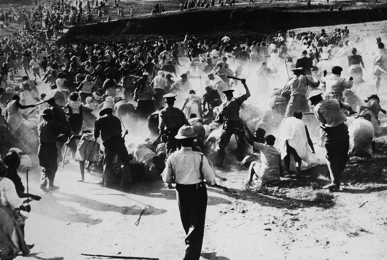 Pemuda Soweto berlutut di depan polisi sambil memegang tangan mereka di udara menunjukkan tanda perdamaian pada 16 Juni 1976, di Soweto, Afrika Selatan.