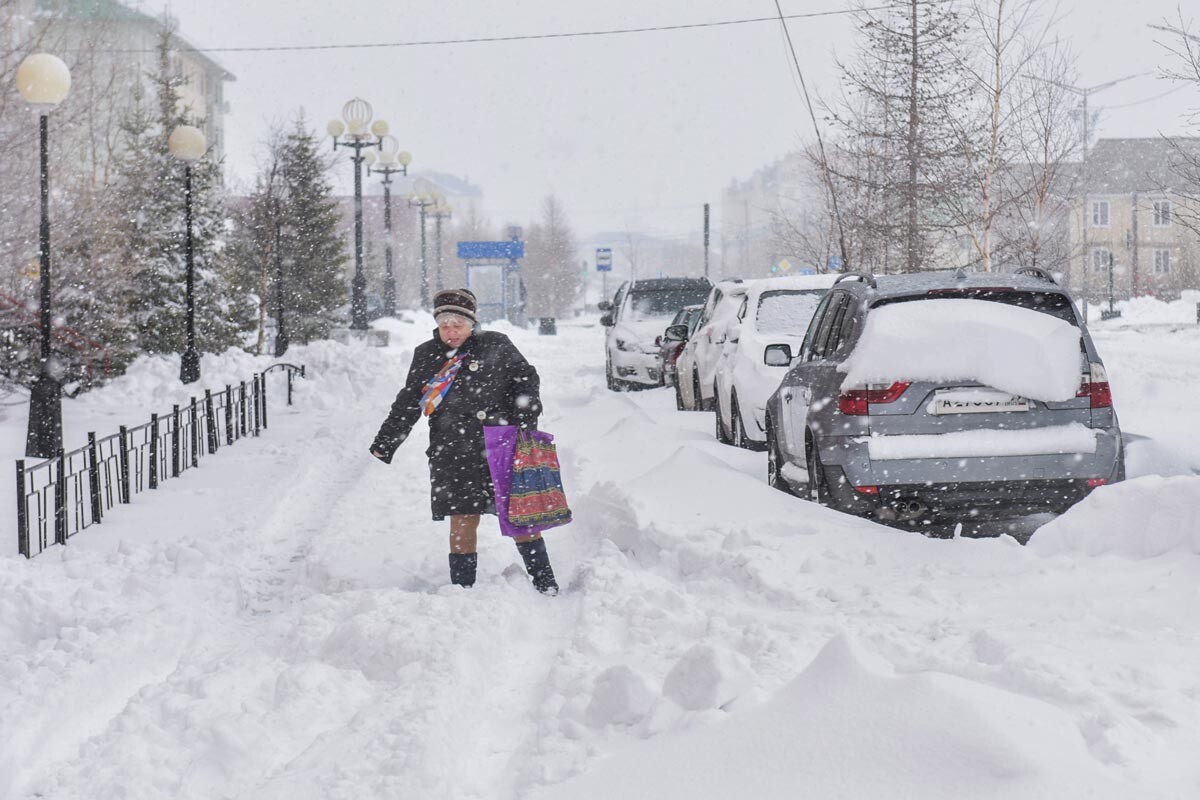 Salechard. Eine Frau während eines Schneefalls auf einer der Straßen der Stadt.