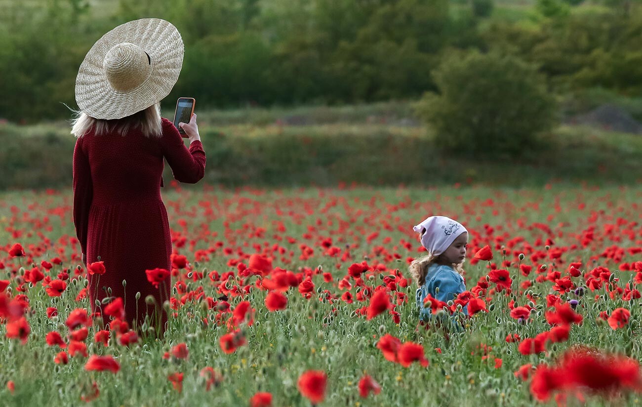 Жена фотографише дете на маковом пољу близу железничке станице Сирењ и села Танковое у Бахчисарајском рејону Крима.