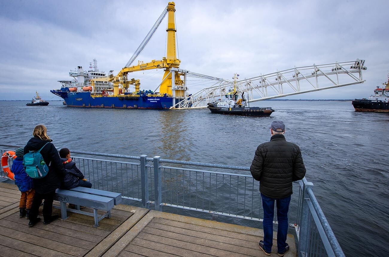 Пролазници посматрају руски брод за постављање цеви „Академик Черски“ док га тегљачи вуку из луке у Балтичко море. Брод је током последњих недеља опремљен додатном опремом у Висмару. Мекленбург – Западна Померанија, Висмар.