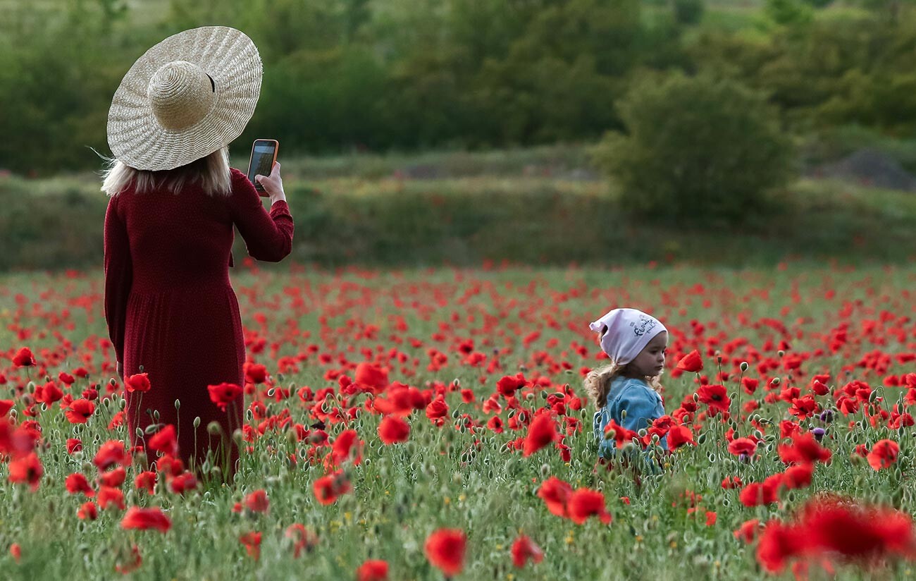  Žena fotografira dijete na makovom polju blizu željezničke stanice Sirenj i sela Tankovoe u Bahčisarajskom rajonu Krima. 