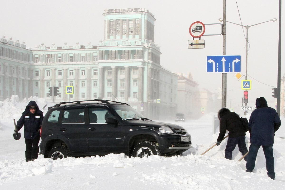 Норилск. Луѓе откопуваат автомобил од снегот додека дува силен ветар. 

