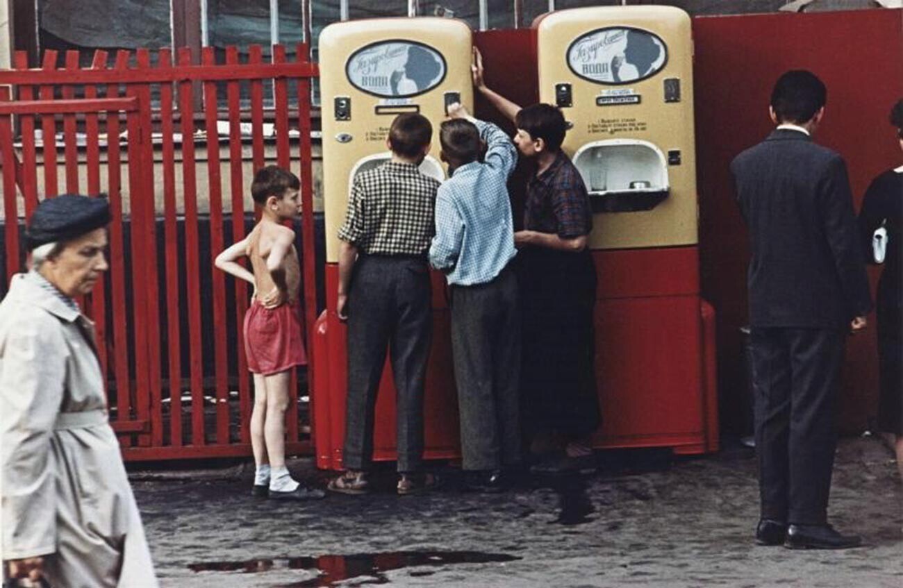 Anak laki-laki sedang di depan mesin penjual otomatis yang menjual soda dengan sirup.